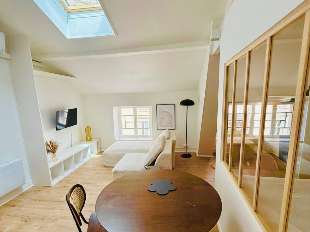 Séjour lumineux avec verrière bois, fenêtre de toit et canapé beige