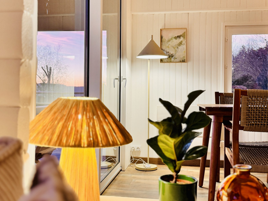 Séjour cosy avec lampes design, table en bois et vue coucher de soleil