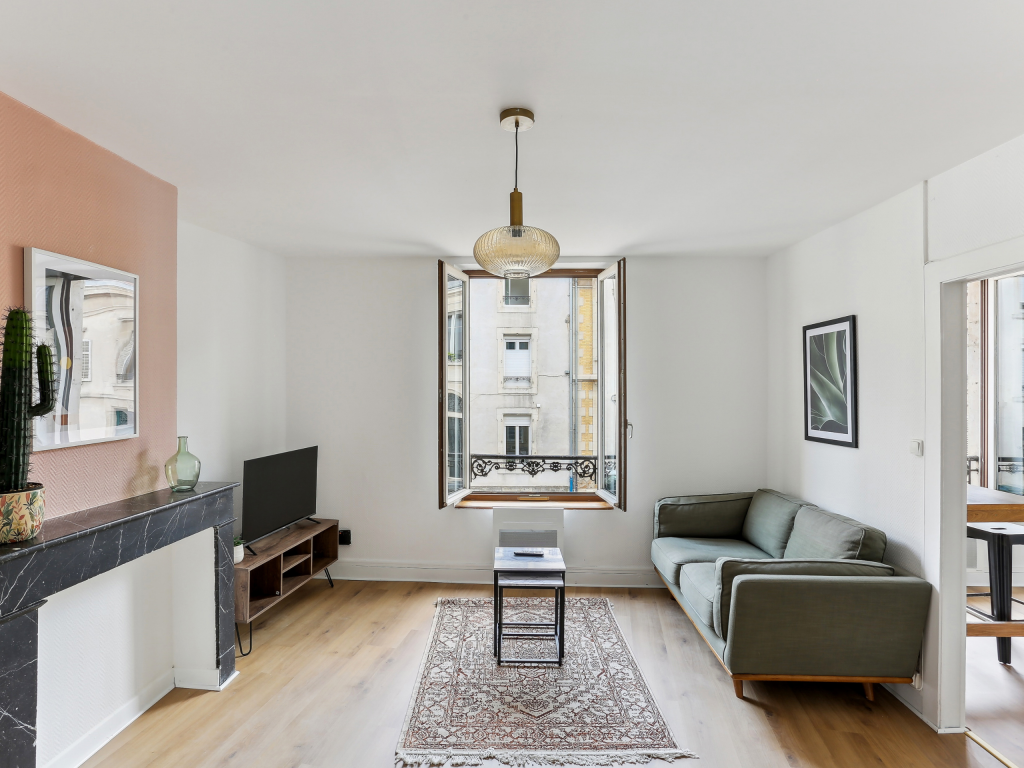 Salon cosy avec canapé gris, parquet au sol et cheminée en marbre noir