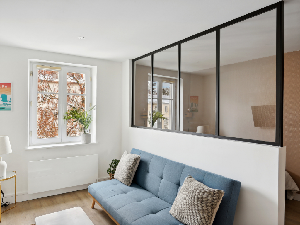 Salon cosy avec canapé bleu et verrière métal noir vitrée