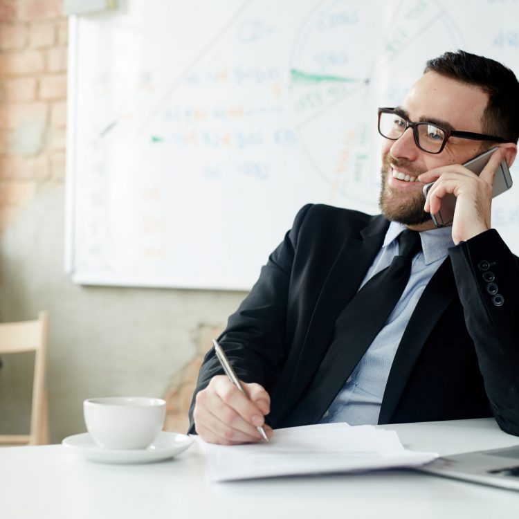 Business leader planning work and speaking on smartphone by workplace